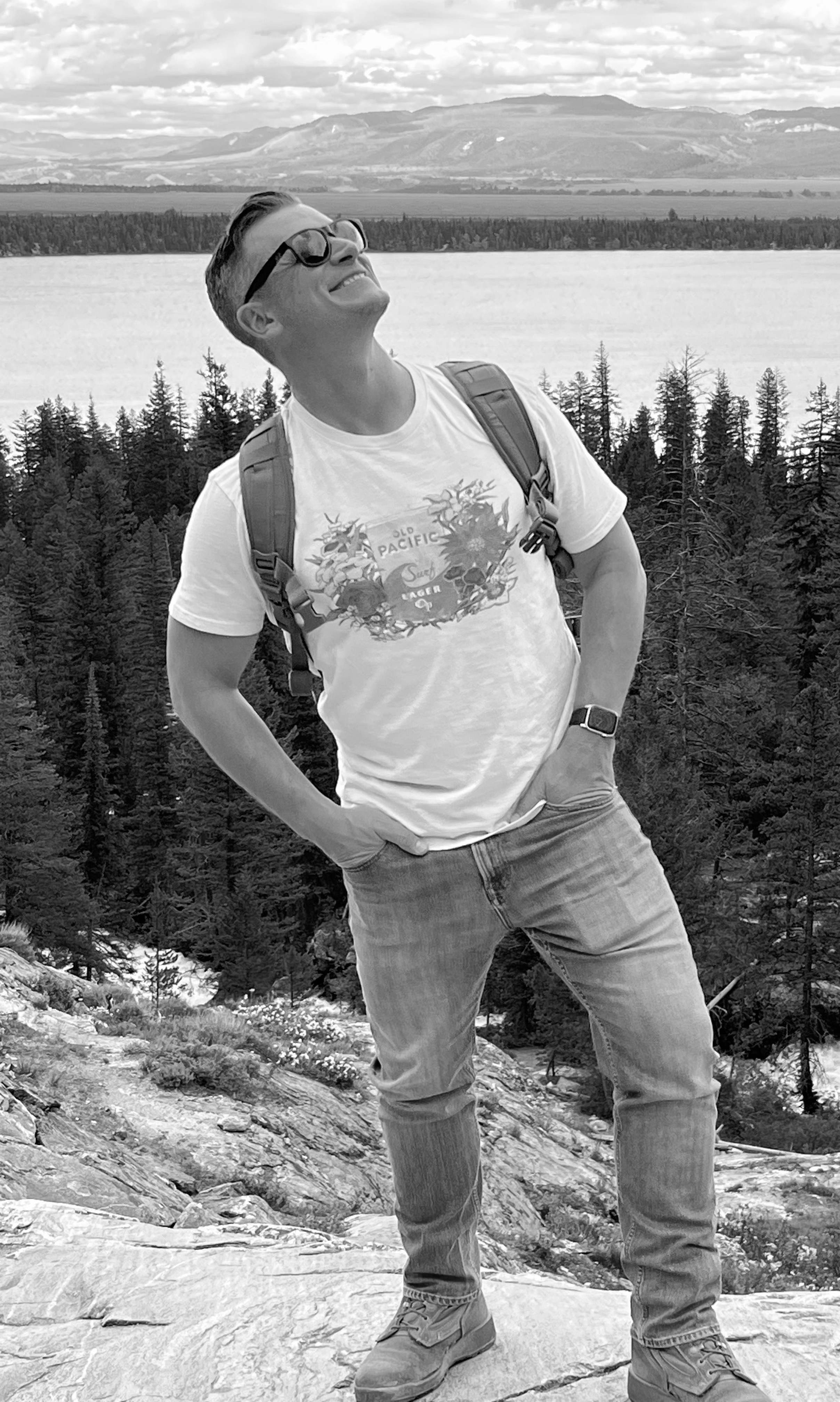 A smiling Rick on top of a mountain looking at the sky.